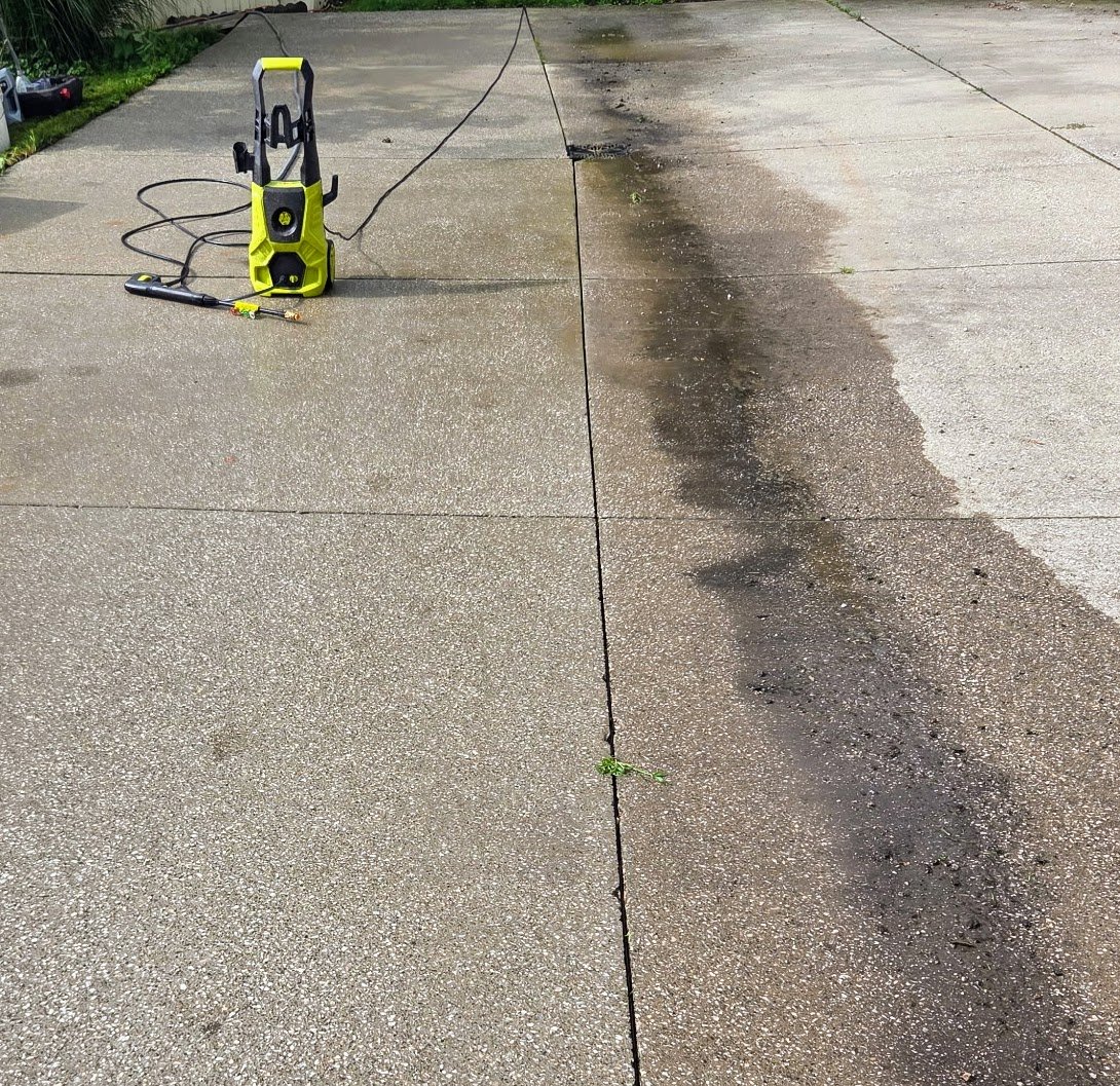 Pressure washing a driveway, showing the difference between a clean and dirty surface.
